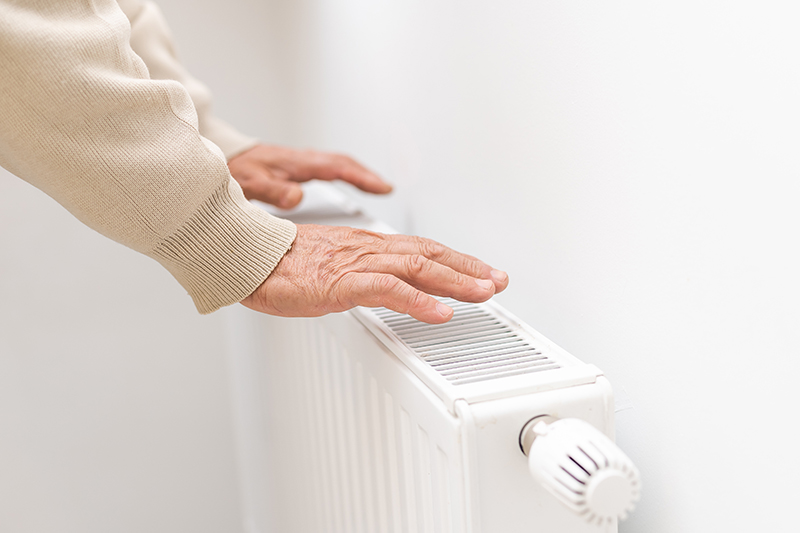 Hand fühlt Temperatur beim Heizkörper