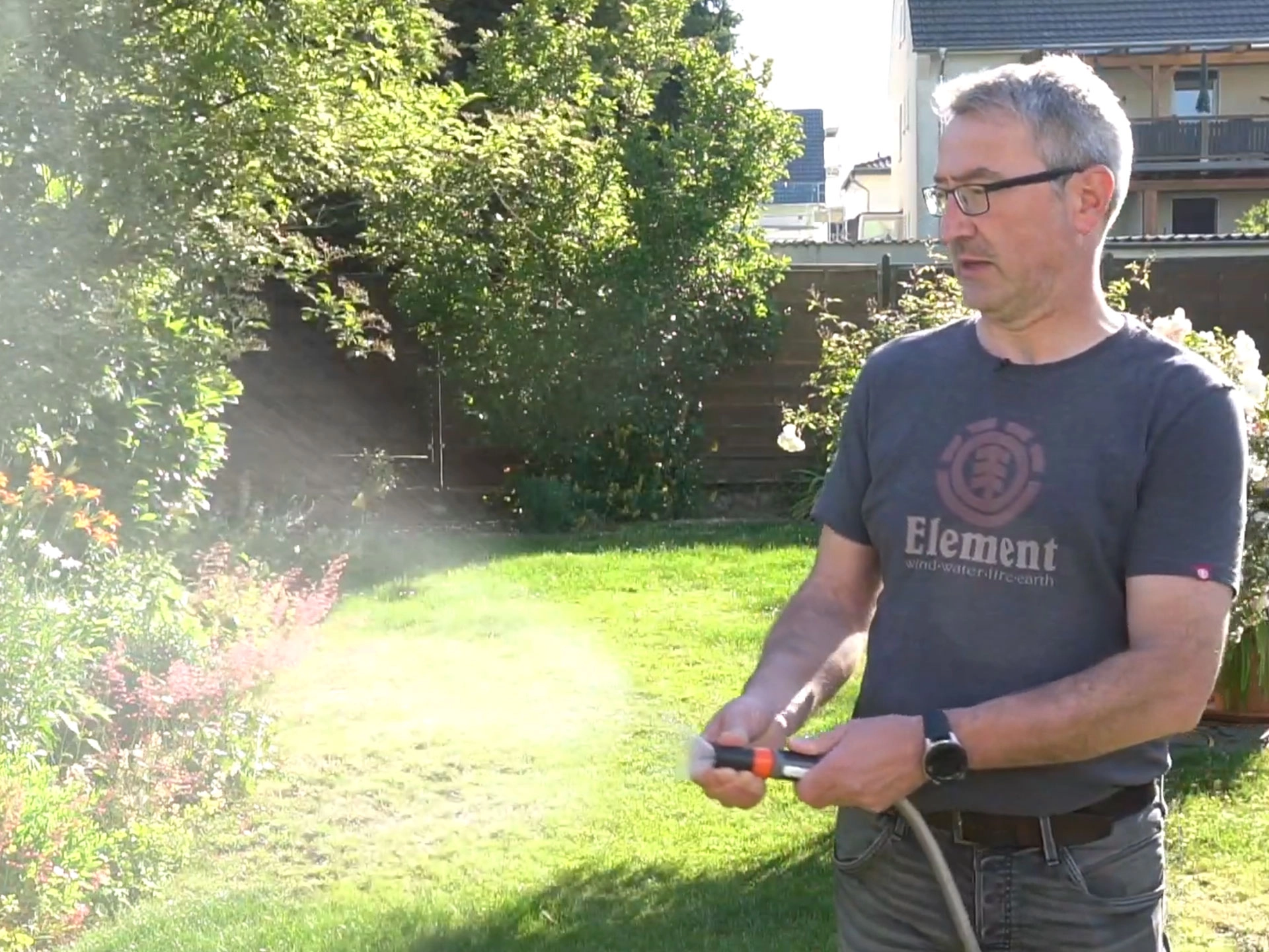 Mann bewässert mit dem Gartenschlauch den Garten