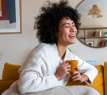 Frau lacht mit Tasse in der Hand