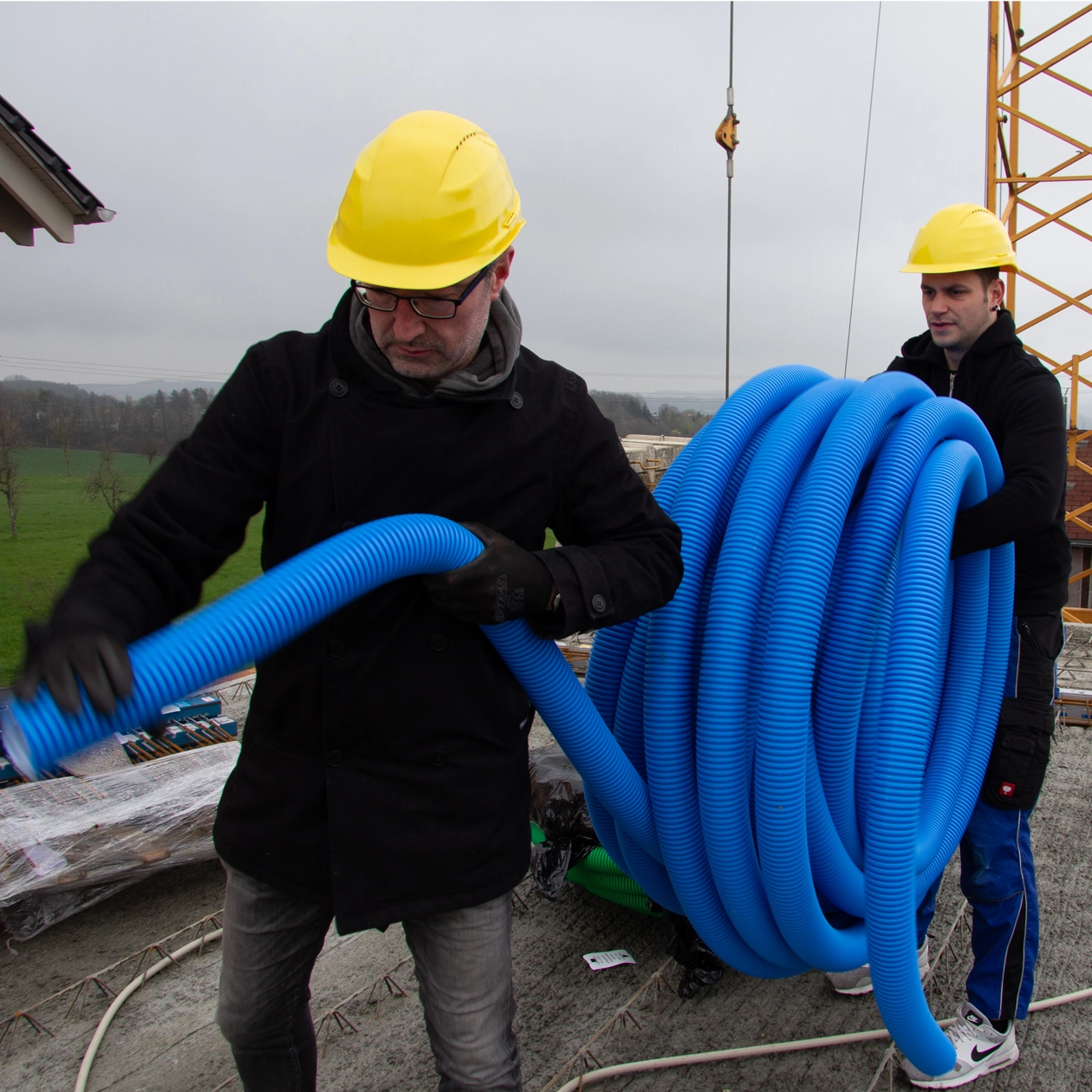 Mann auf dem Bau trägt Lüftungsrohre
